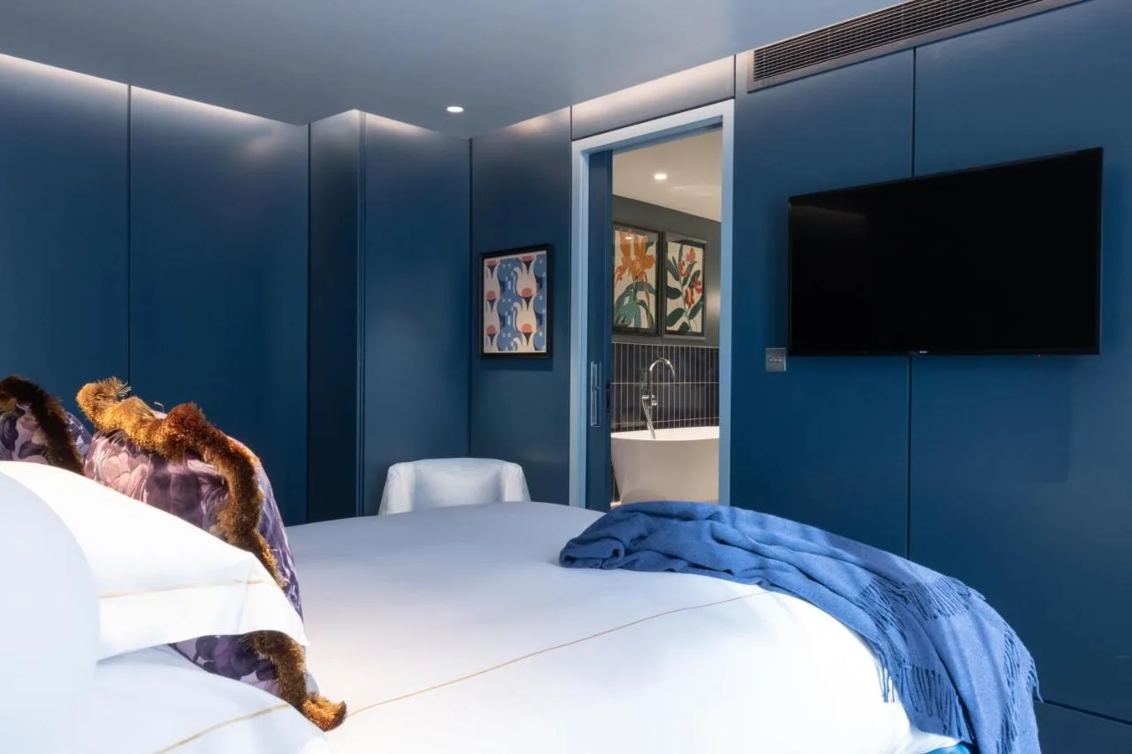 a blue bedroom with a bed and a flat screen tv at Sun Street Hotel Shoreditch in London