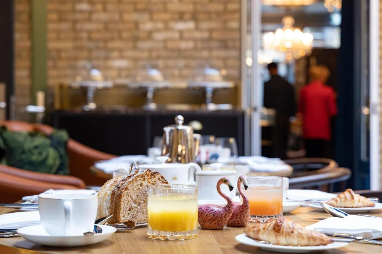 a table with plates of food and glasses of orange juice at Sun Street Hotel Shoreditch in London